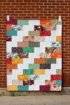 the pinterest app is showing an image of a colorful quilt on a brick wall