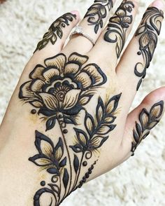 a woman's hand with henna tattoos on it and an intricate flower design