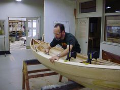 a man working on a wooden boat in a shop