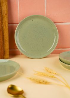 two green plates sitting on top of a table next to a wooden spoon and fork