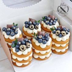 a box filled with lots of cakes covered in frosting and blueberries on top of each other