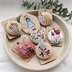 six handmade brooches are sitting on a plate