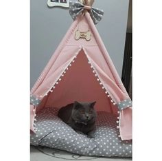 a cat is sitting in a pink teepee with polka dots and a bow on it's head