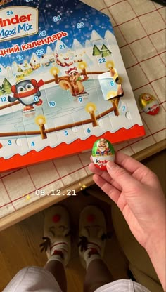 someone is holding up a candy bar in front of a christmas themed puzzle box with santa's reindeers on it