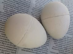 two white eggs sitting on top of an open newspaper