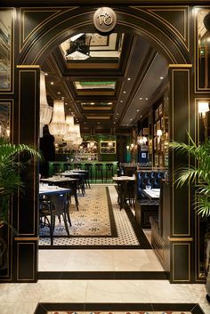 an entrance to a restaurant with tables and chairs in the center, surrounded by potted plants