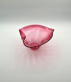 a pink glass bowl sitting on top of a white table