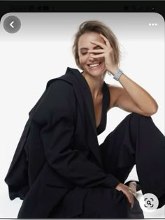 a woman sitting on the ground with her hands behind her head and smiling at the camera