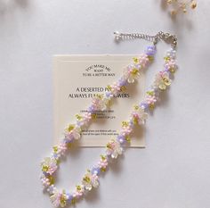 a necklace with flowers on it sitting next to a card