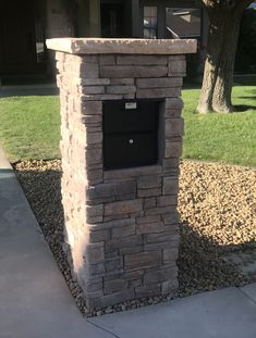 a brick mailbox sitting on the side of a sidewalk