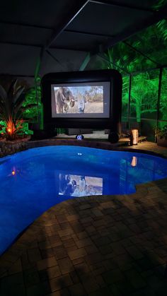 an indoor swimming pool with a projection screen in the center and a television on the wall