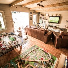 a living room filled with lots of furniture and a train track on top of a wooden floor