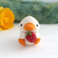 a small stuffed animal with a strawberry in it's hand next to a yellow flower