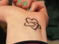 a woman's wrist with a heart tattoo on her left arm and the word love written in black ink