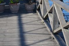 a bird sitting on the edge of a wooden bridge next to some potted plants