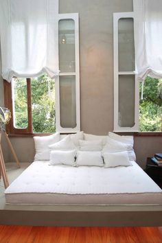 a white bed sitting in front of two windows