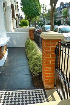 a black and white checkered floor next to a brick wall with an iron gate