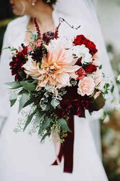 a bride holding a bouquet of red and white flowers