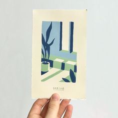 a hand holding up a small card with an image of a cactus in the background