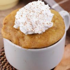 a close up of a dessert in a cup on a wooden table next to a spoon