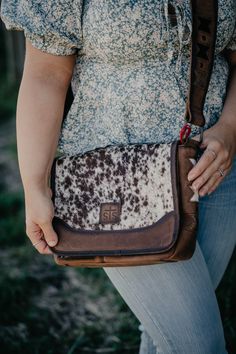 Introducing Roswell Cowhide Crossbody by STS Ranchwear! This collection takes their best selling cowhide collection and elevates it with details like unique aztec cowhide cut-outs in the in genuine full grain veg tan leather crossbody strap. The "Della" Crossbody style is the perfect sized (Bag dimensions: 10" W x 9.5" H x 2.5" D) bag for daily use and features a convenient adjustable crossbody strap and tons of organizational options! You're going to love her! 10 X 9.5 X 2.5" Full grain oiled veg tan leather with cowhide panels and cowhide aztec inlay accents on the side of the bag body and also on the crossbody strap Adjustable and removable leather crossbody strap Top flap with magnetic closure Organzation: 1 exterior slip pocket; under flap- 1 slip pocket, 5 card slots, 1 id slot; 1 in Cowboy Christmas, Mens Winter Boots, Graphic Tee Dress, Veg Tan Leather, Denim Gift, Denim Accessories, Strap Top, Strap Tops, Leather Patches