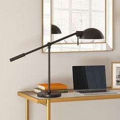 a laptop computer sitting on top of a wooden desk next to a lamp and pictures