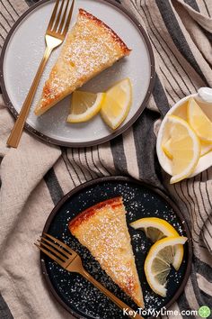 two plates with slices of lemon cake on them next to a fork and bowl of lemons