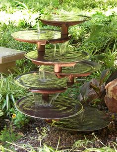 three tiered trays with plants growing on them in front of rocks and grass