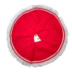 a red and white round pillow with tassels on the bottom, sitting in front of a white background