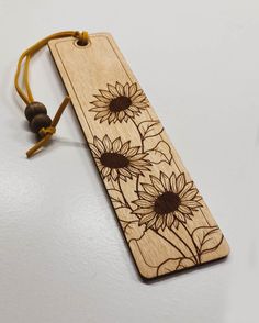 a wooden bookmark with sunflowers engraved on the front and back, hanging from a string