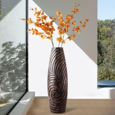 a vase filled with orange flowers sitting on top of a table next to a window