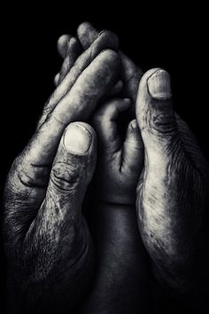 black and white photograph of two hands holding each other with their fingers folded in the middle