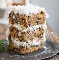 a piece of carrot cake sitting on top of a plate next to some broccoli