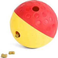 a yellow and red ball with holes in it next to some dog treats on a white background