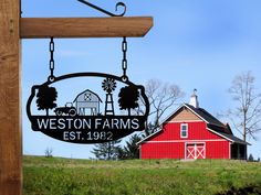 a sign hanging from the side of a wooden pole in front of a red barn