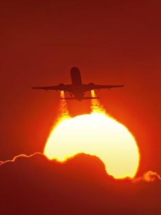 an airplane is flying in the sky at sunset or sunrise with clouds and sun behind it