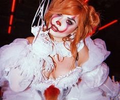 a woman dressed as a clown with red hair and makeup