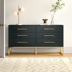 a black and gold dresser in a white room with a potted plant on top