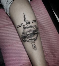 a woman's arm with a tattoo that says trust no one on it and a snake