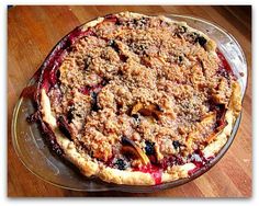 a pie sitting on top of a pan covered in toppings and crumbs