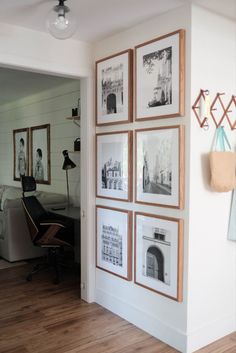 a living room with pictures hanging on the wall and a chair in front of it