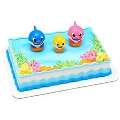 a cake decorated with three little sharks on it's sides and under the water