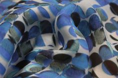 the fabric is blue and brown with black dots on it's edges, as well as an abstract design