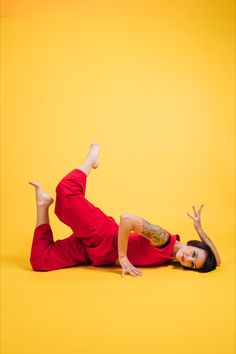 a woman in red is laying on the floor with her legs up and arms out