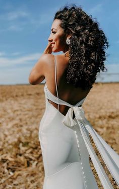 a woman in a white dress is standing in a field with her back to the camera