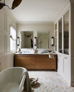 a bathroom with a tub, sink and large mirror on the wall next to it