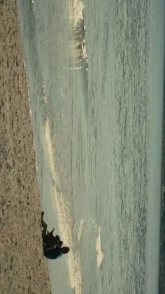 two people standing on the beach next to the ocean