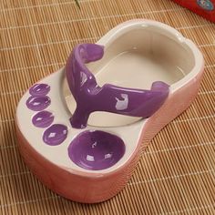 a purple and white ceramic figurine sitting on top of a wooden mat next to a red box