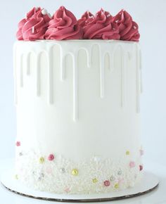 a white cake with pink frosting and sprinkles on the top layer