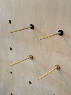 four wooden sticks are arranged on the wall with holes in them and one is stuck to the floor